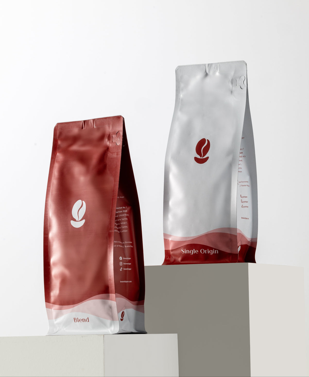 Two coffee bags, one red and one silver with a logo, on a white background.