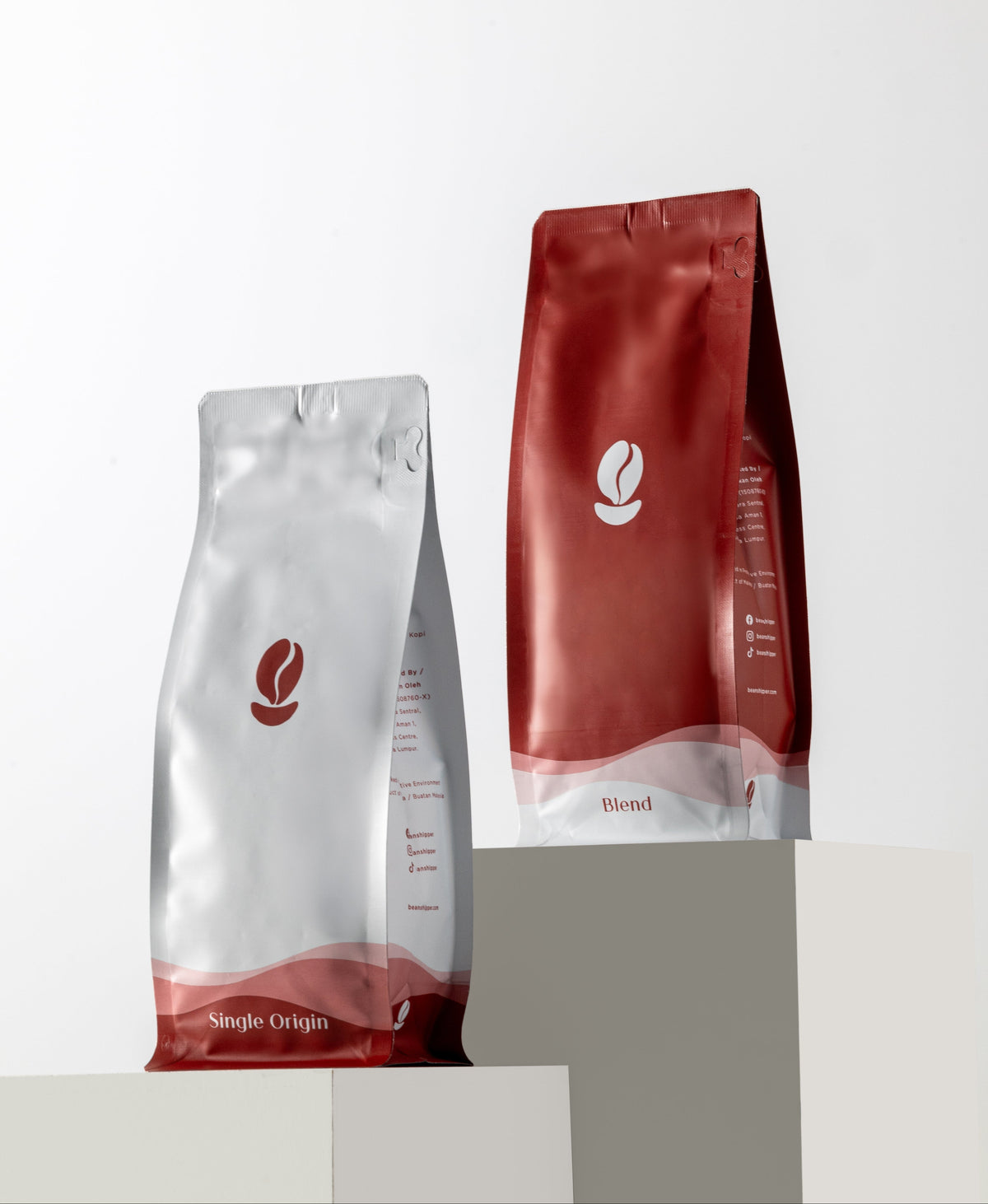 Two coffee bags, one red and one silver, on a white background
