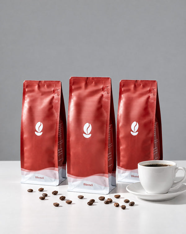 The Trio: three 300g Bean Shipper bags and a cup of black coffee on a white table against a grey wall